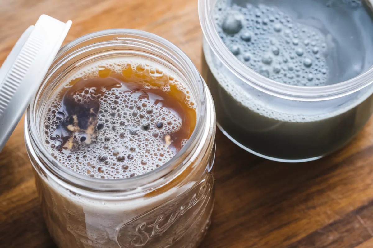 An image showing a side-by-side comparison of active sourdough starter and sourdough discard in jars, highlighting their differences